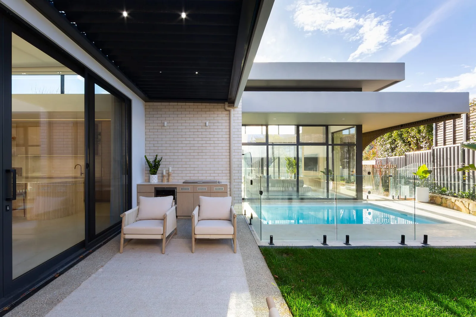 Outdoor seating under the pergola, looking across the lawn to the pool